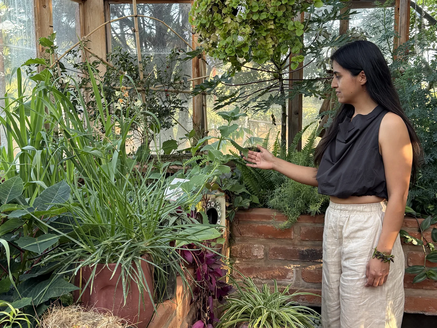 Alicia in conversation with plants in a greenhouse