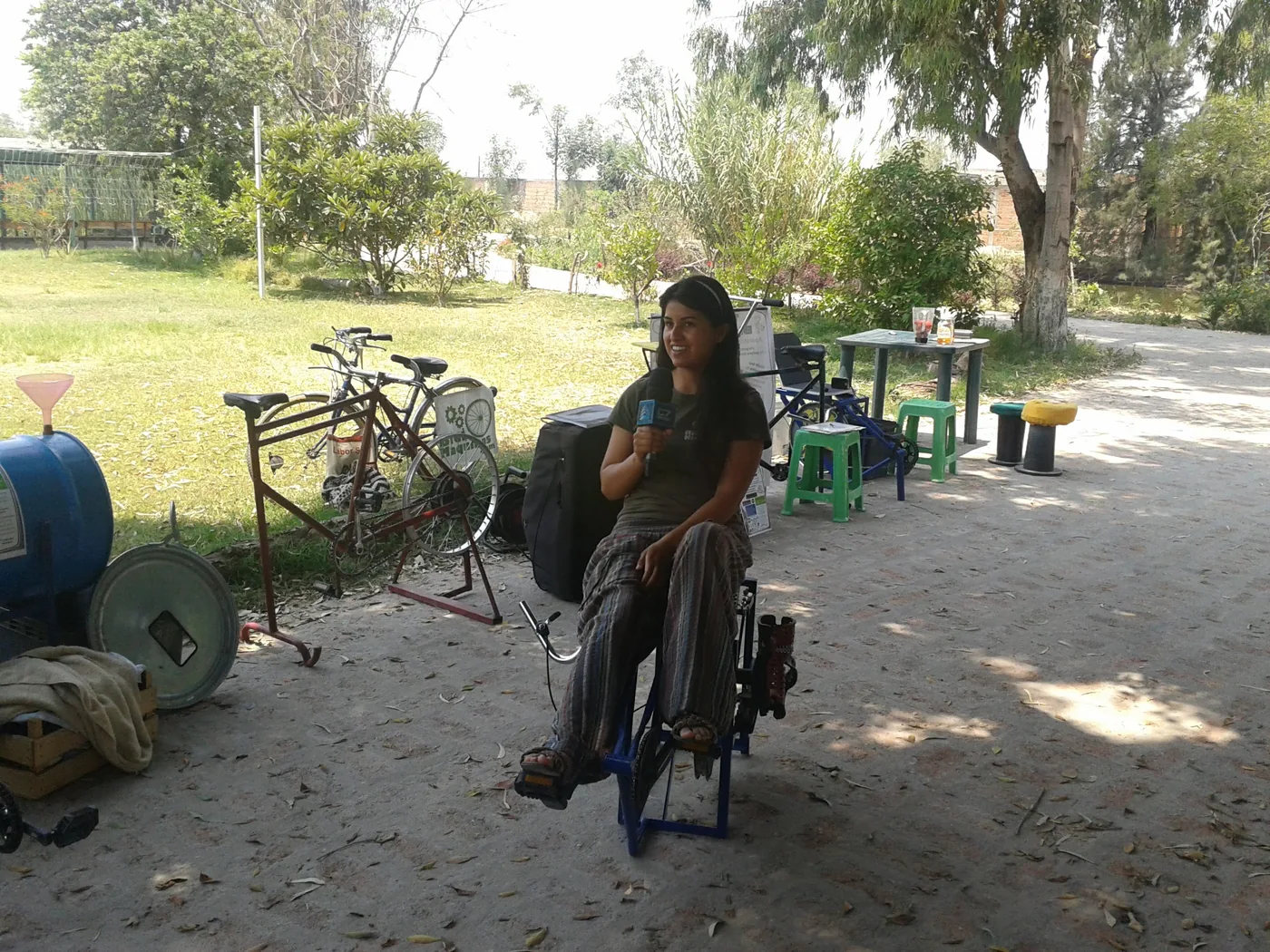Alicia holding a microphone while seated on a pedal-powered machine