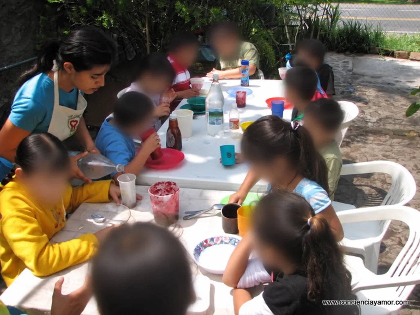 Alicia facilitating an outdoor children’s activity around a table, with children’s faces blurred for privacy